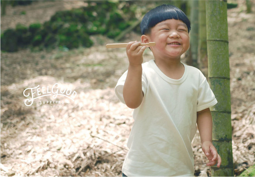 一個小男孩滿面笑容地手舉著元泰竹藝社的減塑竹牙刷